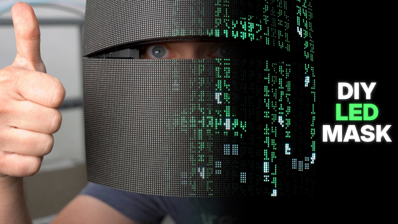 Thumbnail of the YouTube video: The image is split into two halves that blend into each other. On the left there is a well-lit photo of a mask made of flexible LED matrix panels. They form a narrow slit through which a real blue eye is visible and to the left of the panel a hand gives a thumbs up. On the right the shape of the mask continues into a very dark scene in which only glowing pixels of the matrix panels are visible, which form a green constellation of glyphs reminiscent of the Matrix movies.